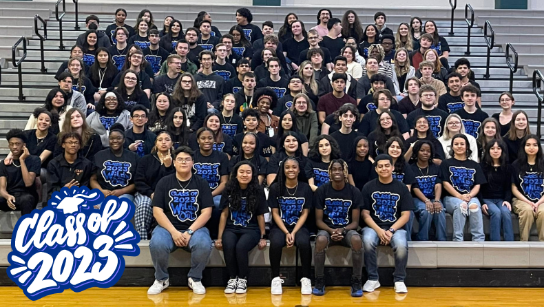 large group of high school seniors seated in the gym wearing matching shirts